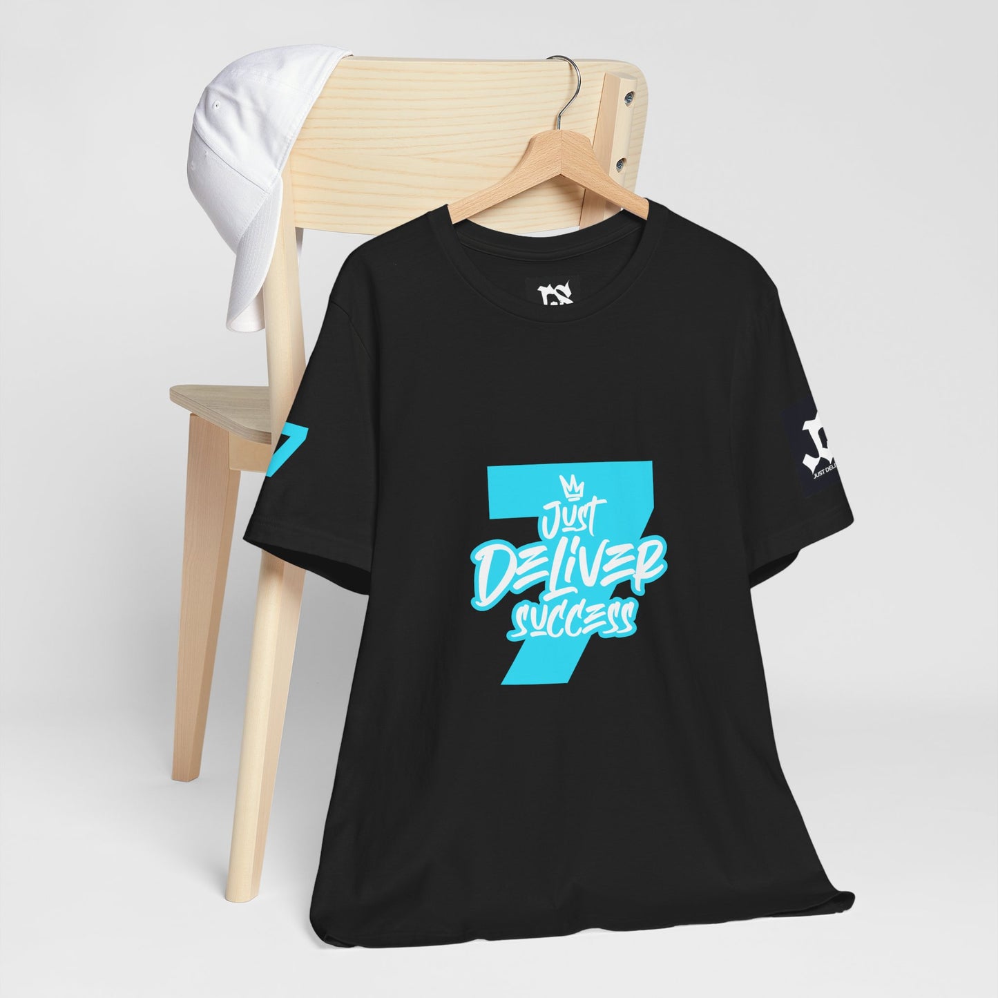 Just Deliver Success Light Blue That City 7 Summer Collection black t-shirt displayed on a wooden chair with a white cap.