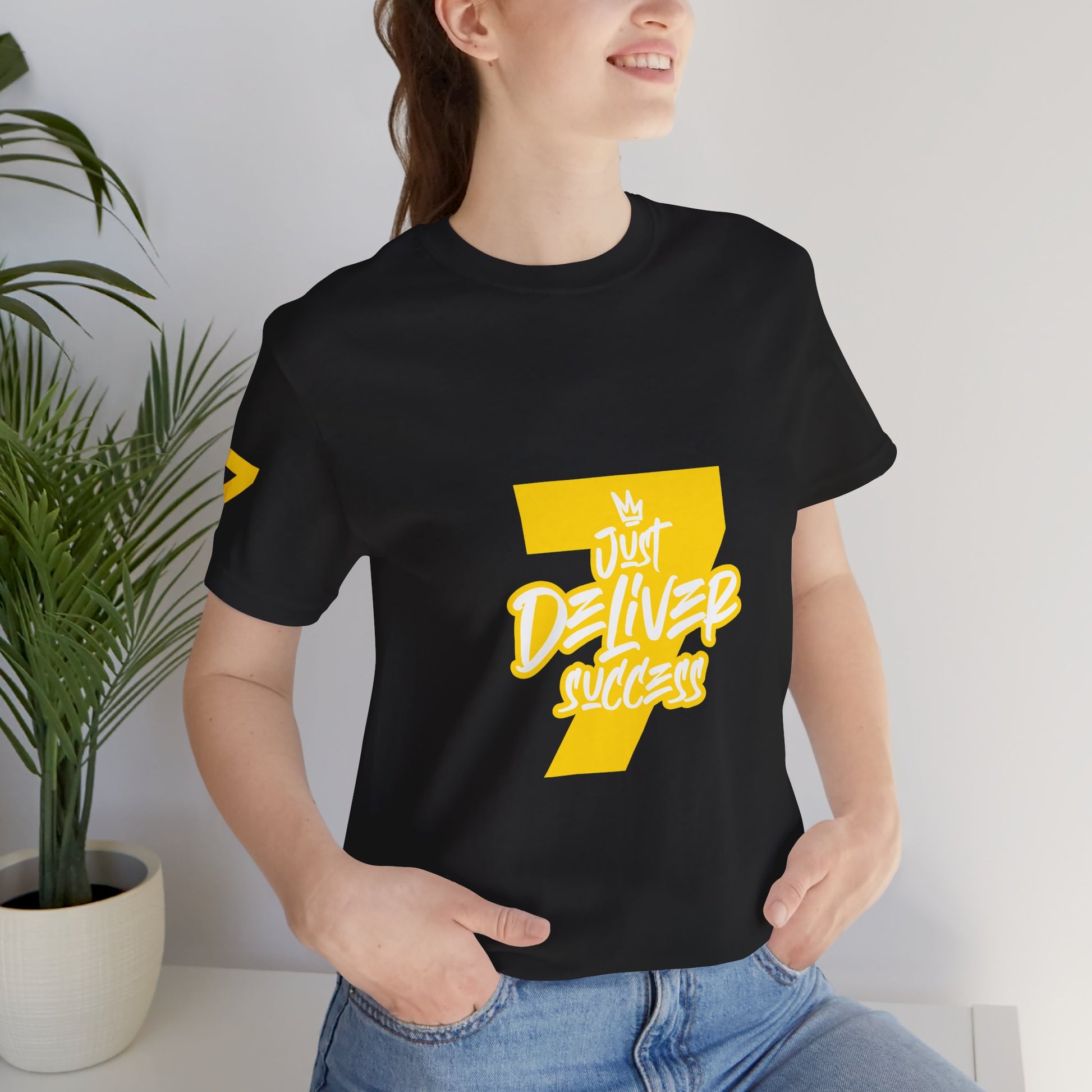 Model wearing a black t-shirt featuring "Just Deliver Success Gold That City 7 Summer Collection" design.